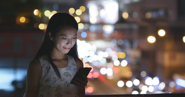 Woman use of smart phone in city at night